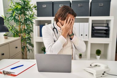 Klinikte çalışan yakışıklı, orta yaşlı bir doktor. Ağlarken yüzünü ellerle kapatan üzgün bir yüz ifadesi var. depresyon kavramı. 