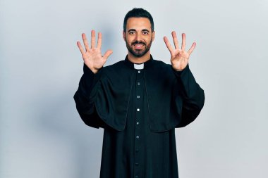 Sakallı, Katolik rahip cüppeli yakışıklı bir adam 9 numaralı parmaklarıyla kendini beğenmiş ve mutlu gülümserken kendini gösterdi.. 