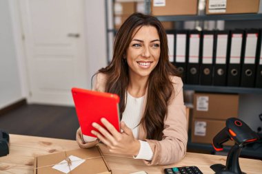 Ofiste dokunmatik ped kullanan Latin kökenli genç bir iş kadını.