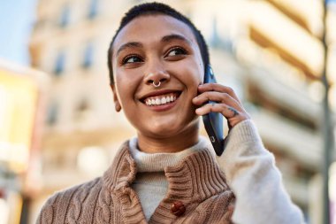 Kısa saçlı, gülümseyen, telefonda konuşan genç İspanyol kadın.