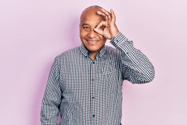 Orta yaşlı, gündelik kıyafetler giyen, el hareketleriyle gülümseyen, mutlu yüzlü parmaklarından bakan Latin bir adam.. 