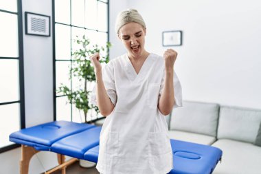 Genç Kafkas fizyoterapist kadın evde çok mutlu ve heyecanlı bir şekilde çalışıyor. Kollarını kaldırıp, gülümseyerek ve başarı için çığlık atarak zafer jesti yapıyor. kutlama konsepti. 