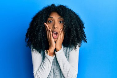 Afro saçlı Afrikalı bir kadın kışlık süveter giyiyor. Korkuyor ve şoka uğruyor. Şaşırıyor ve şaşırıyor. 