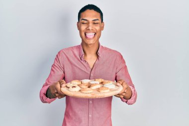 Genç Afro-Amerikalı elinde pasta tepsisi, dilini dışarı çıkaran komik bir ifadeyle mutlu bir adam.. 