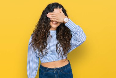 Günlük kıyafetler giyen, gülümseyen ve gülen genç İspanyol kız şaşırmak için gözlerini kapatıyor. kör kavram. 