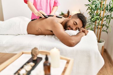 Güzellik merkezinde siyah taşlarla masaj yaptıran adam..