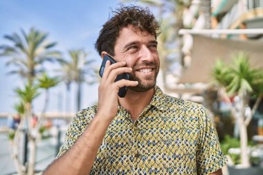 Genç İspanyol adam gülümsüyor. Kendine güveniyor. Sokakta akıllı telefondan konuşuyor.