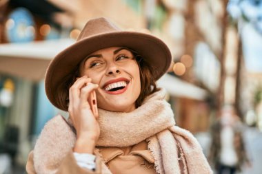 Şık giyinen genç İspanyol kadın şehirdeki akıllı telefondan konuşuyor..