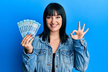 Bangladeş banknotları tutan genç İspanyol kadın. Tamam imzasını atıyor. Parmaklarıyla imzalıyor, gülümsüyor. 