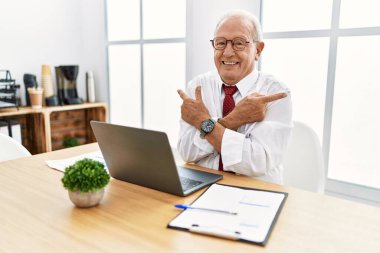 Ofiste çalışan üst düzey bir adam bilgisayarla her iki tarafı da parmaklarıyla işaret ediyor, farklı yönlere. 