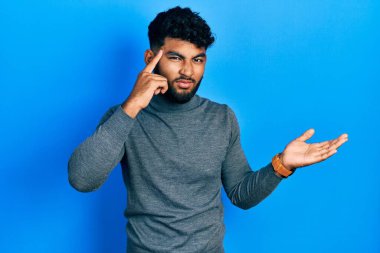 Balıkçı yaka kazak giyen sakallı bir Arap 'ın kafası karışmış ve avuç içi açık fotokopi alanı göstermekten rahatsız olmuş. Bunu bir düşün.. 