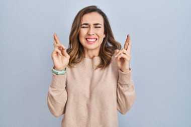 İzole edilmiş arka planda duran genç bir kadın umut ve gözlerin kapalı bir şekilde gülümseyerek bana işaret ediyor. Şans ve batıl inançlar. 