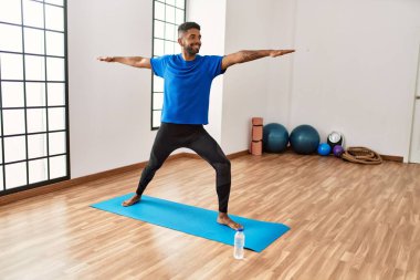 Yakışıklı İspanyol adam egzersiz yapıyor ve yoga minderinde geriniyor. Spor salonunda esneklik ve antrenman yapıyor.