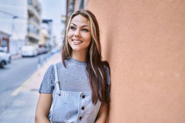 Genç beyaz kız gülümseyerek şehirde mutlu mesut duruyor..