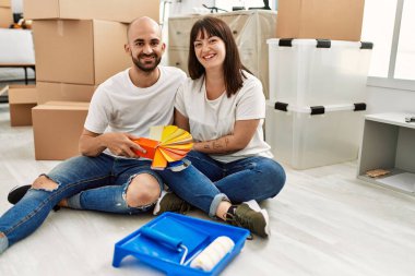 Genç İspanyol çift mutlu bir şekilde gülümsüyor. Yeni evinde boya rengi seçiyor..