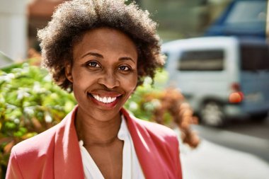 Güzel bir iş adamı Afro saçlı Amerikalı kadın şehirde mutlu ve kendinden emin bir şekilde gülümsüyor.