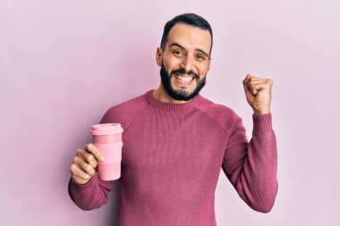 Sakallı genç adam bir fincan kahve içiyor gururla haykırıyor, zaferi kutluyor ve kollarını kaldırdığında çok heyecanlanıyor. 