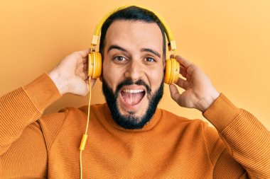 Sakallı genç adam kulaklıkla müzik dinliyor. Çılgınca kutlama yapıyor ve başarıya hayret ediyor. Gözleri açık, heyecanlı çığlıklar atıyor.. 