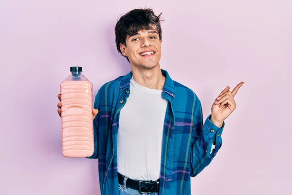 Przystojny Hipster Młody Człowiek Trzymając Butelkę Detergentu Uśmiechając Się Szczęśliwy — Zdjęcie stockowe