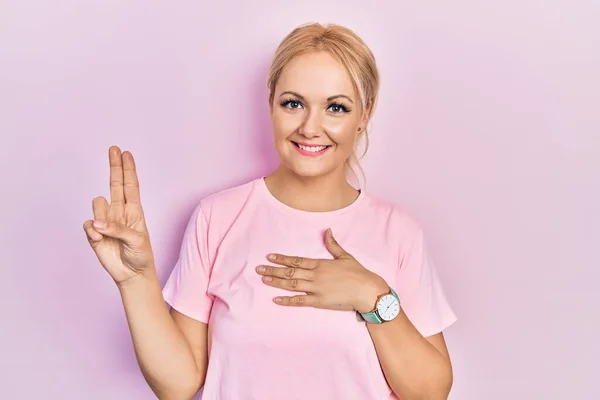 Молода Блондинка Повсякденній Рожевій Сорочці Посміхається Лаятися Рукою Грудях Пальцях — стокове фото