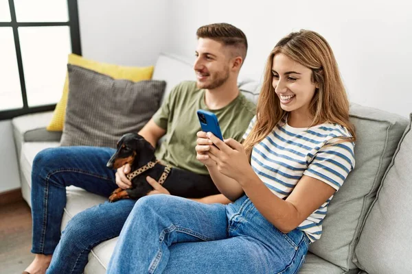 Junges Hispanisches Paar Lächelt Glücklich Mit Smartphone Auf Dem Sofa — Stockfoto