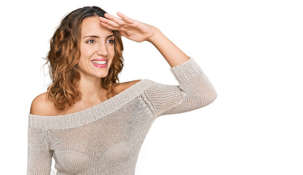 Красивая молодая кавказская женщина в повседневной одежде очень счастливая и улыбающаяся, глядя вдаль с рукой над головой. поиск концепция. 