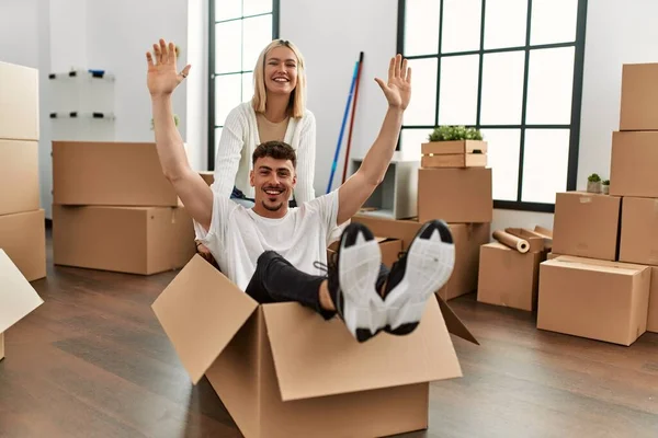 Young caucasian couple smiling happy playing with cardboard box as a car at new home.