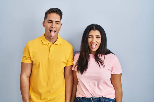 Young Couple Standing Isolated Background Sticking Tongue Out Happy Funny —  Fotos de Stock