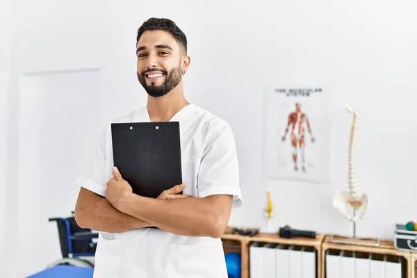 Junger Arabischer Mann Physiotherapeutenuniform Hält Klemmbrett Klinik — Stockfoto