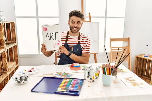 Joven Artista Árabe Sonriendo Feliz Sosteniendo Cuaderno Con Palabra Arte — Foto de Stock