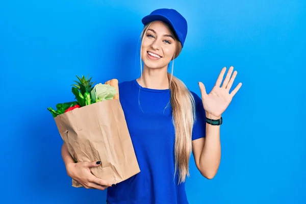 Junge Kaukasische Frau Kurieruniform Mit Lebensmitteln Aus Dem Supermarkt Verzichtet — Stockfoto