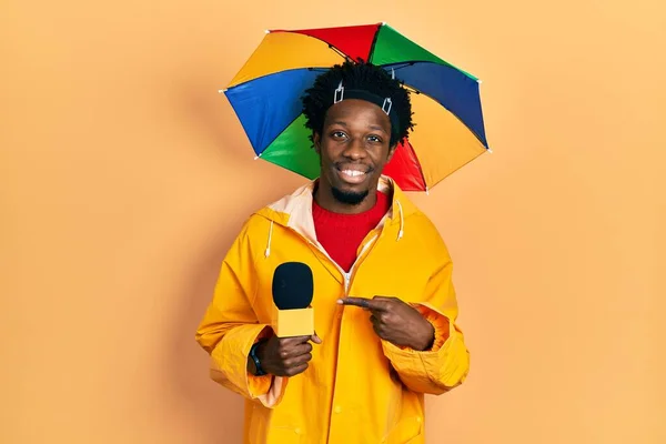 Young African American Journalist Man Wearing Yellow Raincoat Umbrella Cap — Fotografia de Stock