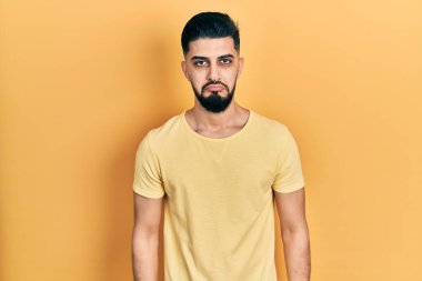 Sakallı, sıradan, sarı tişörtlü yakışıklı bir adam. Depresyonda ve endişeli, sinirli ve korkmuş. hüzünlü ifade. 