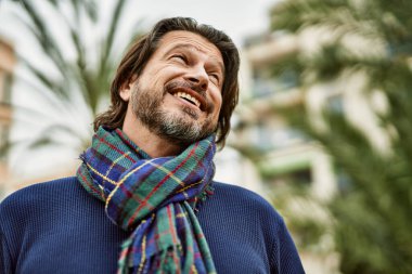 Parkta gülümseyen orta yaşlı yakışıklı adam.