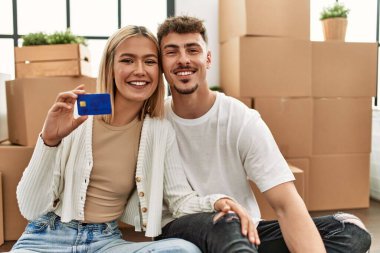 Yeni evinde oturan, mutlu gülümseyen beyaz bir çift..