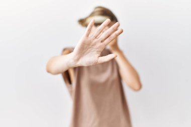 İzole edilmiş arka planda duran genç sarışın kadın elleriyle gözlerini kapatıyor ve üzgün ve korku ifadeleriyle jest yapıyor. utangaç ve olumsuz kavram. 