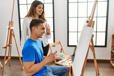 Öğrenci ve öğretmen resim yaparken gülümsüyor..