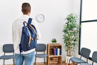 Genç İspanyol adam, öğrenci çantasıyla bekleme odasında bekliyor.