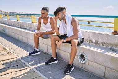 İki İspanyol erkek, deniz kenarında rahat rahat oturuyorlar.