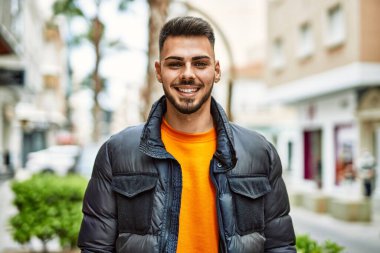 Yakışıklı, sakallı, neşeli ve kendine güvenen, kışlık palto giyen bir İspanyol.