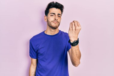 Gündelik tişört giyen İspanyol genç adam İtalyan jesti yapıyor. Elleri ve parmakları ile kendinden emin bir ifade. 