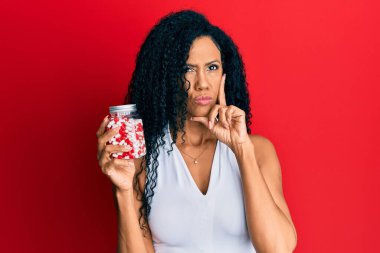 Orta yaşlı Afro-Amerikalı kadın elinde haplarla ciddi bir yüz ifadesi var. Çene ve çeneyle ilgili sorular soruyor. Kafa karıştırıcı bir fikir. 