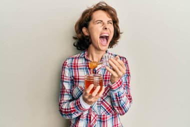 Genç esmer kadın taze bal tutuyor kızgın ve kızgın çığlık atıyor sinirli ve öfkeli, öfkeyle bağırıyor yukarı bakıyor. 