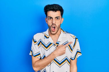 Gündelik giysiler giyen genç İspanyol adam parmaklarını yana doğru göstererek şaşırdı, ağzı açık hayret içinde kaldı.. 