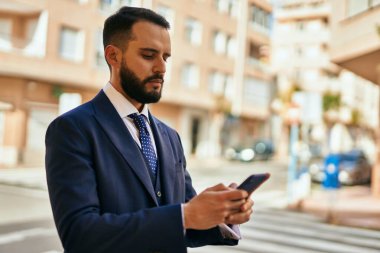 Şehirde akıllı telefon kullanan genç bir iş adamı..