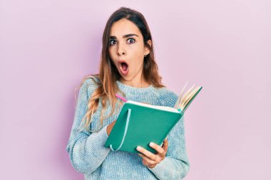 Genç İspanyol kız kitap okuyor ve yazıyor. Şaşırmış ve şaşırmış bir ifade, korku ve heyecanlı bir yüz.. 