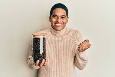 Elinde kahve çekirdeği dolu kavanozla genç, yakışıklı İspanyol adam gururla bağırıyor, zaferi kutluyor ve kollarını kaldırdığı için çok heyecanlı. 