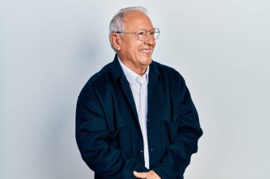 Gri saçlı, sıradan giyinmiş, gözlüklü, yüzünde gülümsemeyle yan yana bakan son sınıf öğrencisi. Kendinden emin gülen. 