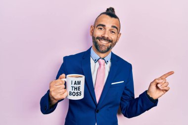 Genç İspanyol adam patron kahve fincanından içiyor. Gülümsüyor, mutlu bir şekilde elini ve parmağını yana uzatıyor. 