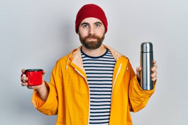 Sakallı, elinde kahve fincanı olan beyaz bir adam ve komik yüzüyle termo şişen yanaklar. Ağzı havayla şişer, havayı yakalar.. 